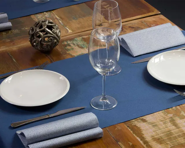 Camino de mesa azul sobre mesa de madera con servilleta gris