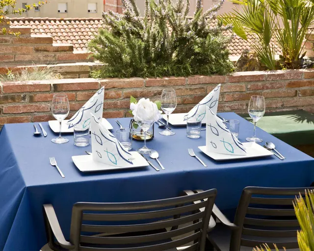 Mesa de terraza con mantel azul y servilletas decoradas