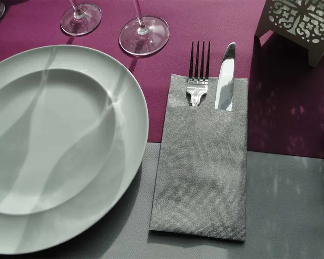 Servilleta portacubiertos gris sobre mantel granate