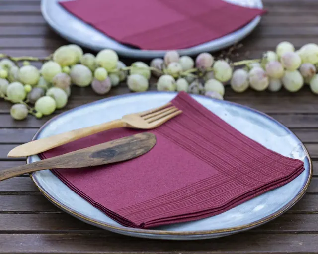 Servilletas burdeos sobre plato con uvas