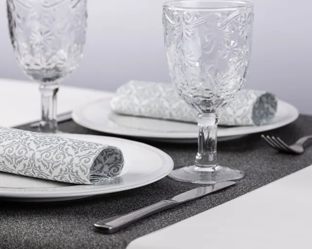 Servilletas grises estampadas enrolladas sobre plato blanco